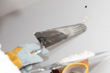 Plasterer home improvement handyman worker with putty knife working on apartment wall filling