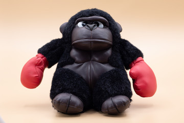 Stuffed toy gorilla boxer with angry face posing on a pale yellow background