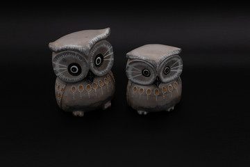 Naklejka premium Figure of a pair of wooden owls one bigger than another on black background