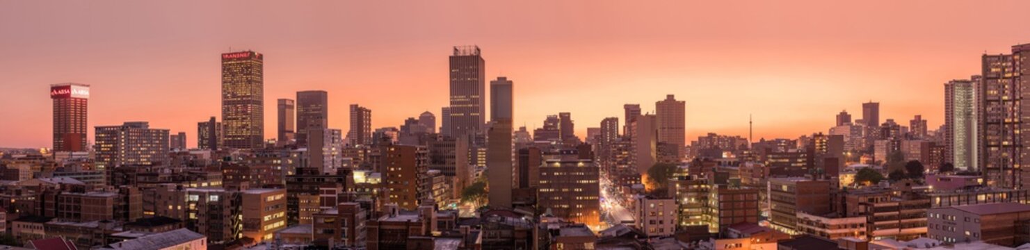 A beautiful and dramatic panoramic photograph of the Johannesburg city skyline, taken on a golden evening after sunset.