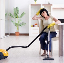 Senior old woman tired after vacuum cleaning house