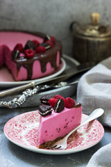 Currant mousse cake decorated with pieces of oreo cookies and raspberries.
