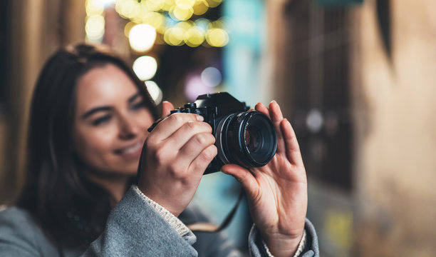 Photographer girl with retro camera take photo on background bokeh light in night city, Blogger photoshoot concept. Tourist  photo hobby. Outdoor portrait smile woman with video technology.