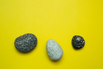 Sea stones on a yellow background. The concept of summer. Copy space.