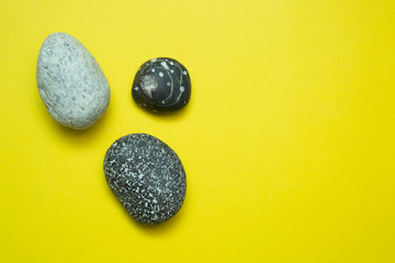 Sea stones on a yellow background. The concept of summer. Copy space.