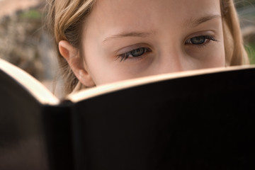  Cute schoolgirl reading the book in the open air, close up