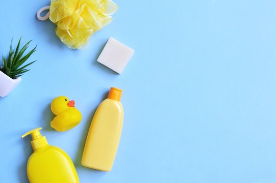 Flat lay beauty photography yellow sponge, natural shampoo, herbal liquid soap, rubber duck on a blue background. Mockup