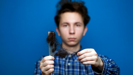 Balding problem men. Teen hand holding loss hair comb
