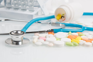 Medical pills, antibiotics, drugs and a stethoscope on white table