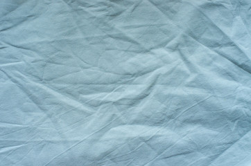 Top view of wrinkles on an unmade bed sheet after waking up in the morning.