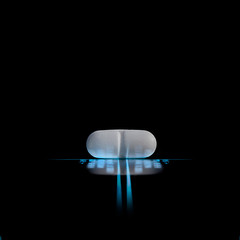 white pill on a luminous lines and blurred data on the black background with reflection