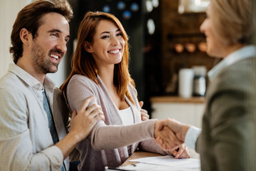 Young happy couple greeting with real estate agent at their home. © Drazen