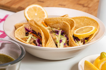 Homemade chicken tacos with hot Jalapeno peppers sauce and lime close up on white background