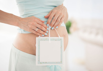 belly of a pregnant woman holding a tablet in her hands