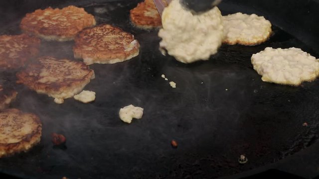 Cooking tasty potato pancakes in a large black cauldron, street food concept