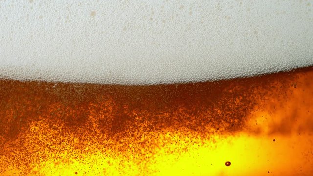 Super Slow Motion Detail Shot of Rippling Beer Bubbles and Foam in Glass at 1000fps.
