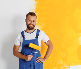 Happy man worker paints wall in   apartment.