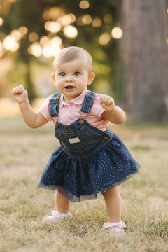Eight month baby first time stand up. Adorable little girl made firs step in her life. Fantactic moment. Summer park
