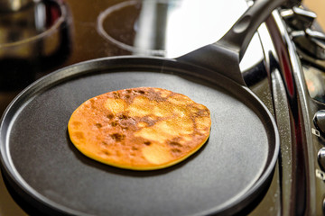 pancake frying pan with crepe pancake cooking on cooker in kitchen