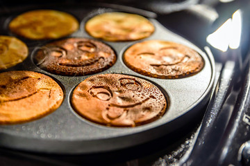 pancake frying pan with smile face pancake cooking on cooker in kitchen