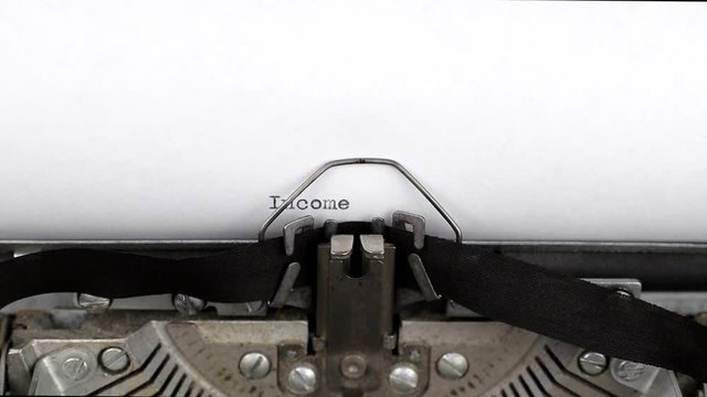Typing a text income tax 2020 close-up view. Old vintage typewriter with a white empty sheet of paper. Concept of finance, paperwork and bookkeeping
