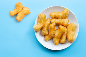 Deep-fried dough stick, chinese bread stick on white dish. Blue background