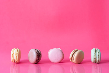Close Up Fresh Colorful Macaroons In A Row Isolated On Pink Background, Sweet Colorful Biscuits Heap Lined Up With Reflection On Table