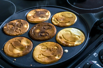 pancake frying pan with smile face pancake cooking on cooker in kitchen
