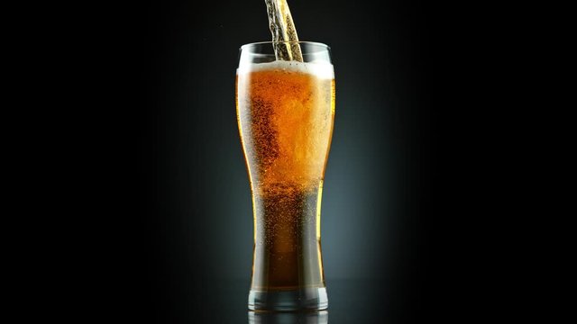 Super Slow Motion Shot of Pouring Fresh Beer into Glass on Black Background at 1000fps.