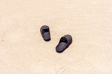 Black rubber slippers on the sand near the sea in africa desert