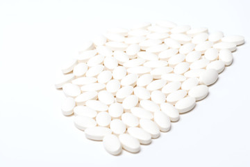Fototapeta na wymiar A large number of tablets of white oval-shaped tablets on a white background. View from above. Isolated