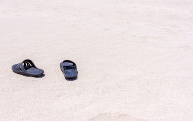 Black rubber slippers on the sand near the sea in africa desert