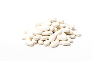 A pile of white oval-shaped tablets on a white background.