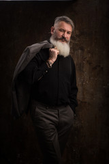 Portrait of a Middle Age Man with Beard and Mustache Posing in Formal Wear on a Dark Backdrop, selective focus