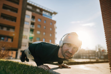 Young smiling athlete doing push-ups on the street.