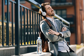 Relaxed businessman enjoying in music over headphones in the city.