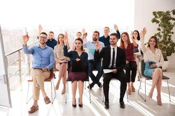 Fototapeta premium People raising hands to ask questions at business training indoors