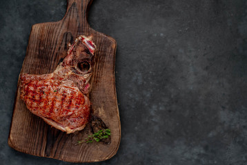 Grilled beef steak with spices on a cutting board on a stone background with copy space for your text