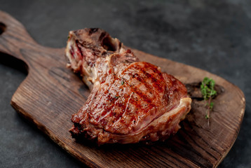 grilled beef steak with spices on a cutting board on a stone background