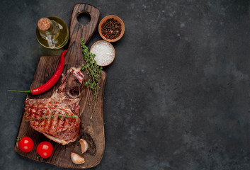 Fototapeta na wymiar Grilled beef steak with spices on a cutting board on a stone background with copy space for your text