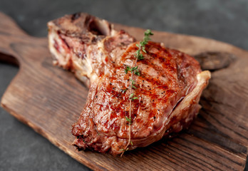 grilled beef steak with spices on a cutting board on a stone background