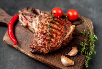 grilled beef steak with spices on a cutting board on a stone background