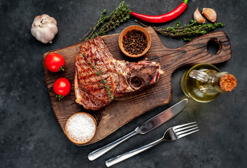 grilled beef steak with spices on a cutting board on a stone background