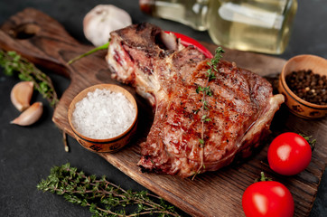 grilled beef steak with spices on a cutting board on a stone background