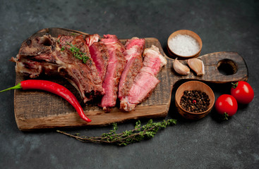 grilled beef steak with spices on a cutting board on a stone background