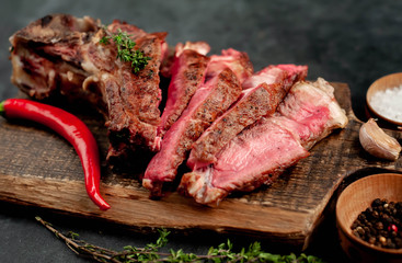 grilled beef steak with spices on a cutting board on a stone background
