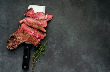 Grilled beef steak with spices and a bottle of wine on a stone background with copy space for your text.