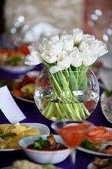 Beautiful fresh spring white tulips for Mother's Day in glass vase on a table. Wedding day, decoration