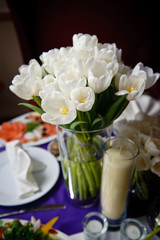 Beautiful fresh spring white tulips for Mother's Day in glass vase on a table. Wedding day, decoration