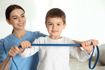 Orthopedist working with little boy in hospital gym